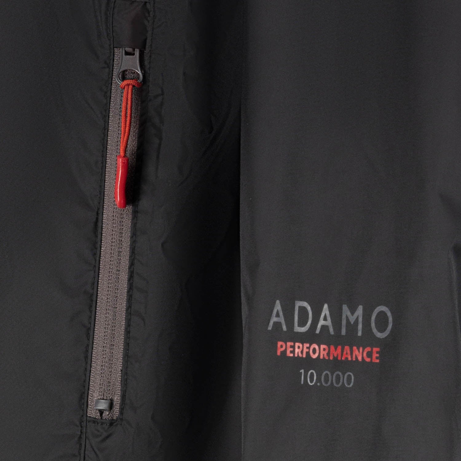 Detailansicht der ADAMO Übergrößen Herren-Regenjacke "Virginia" in Schwarz, Reißverschlusstasche und Performance-Logo